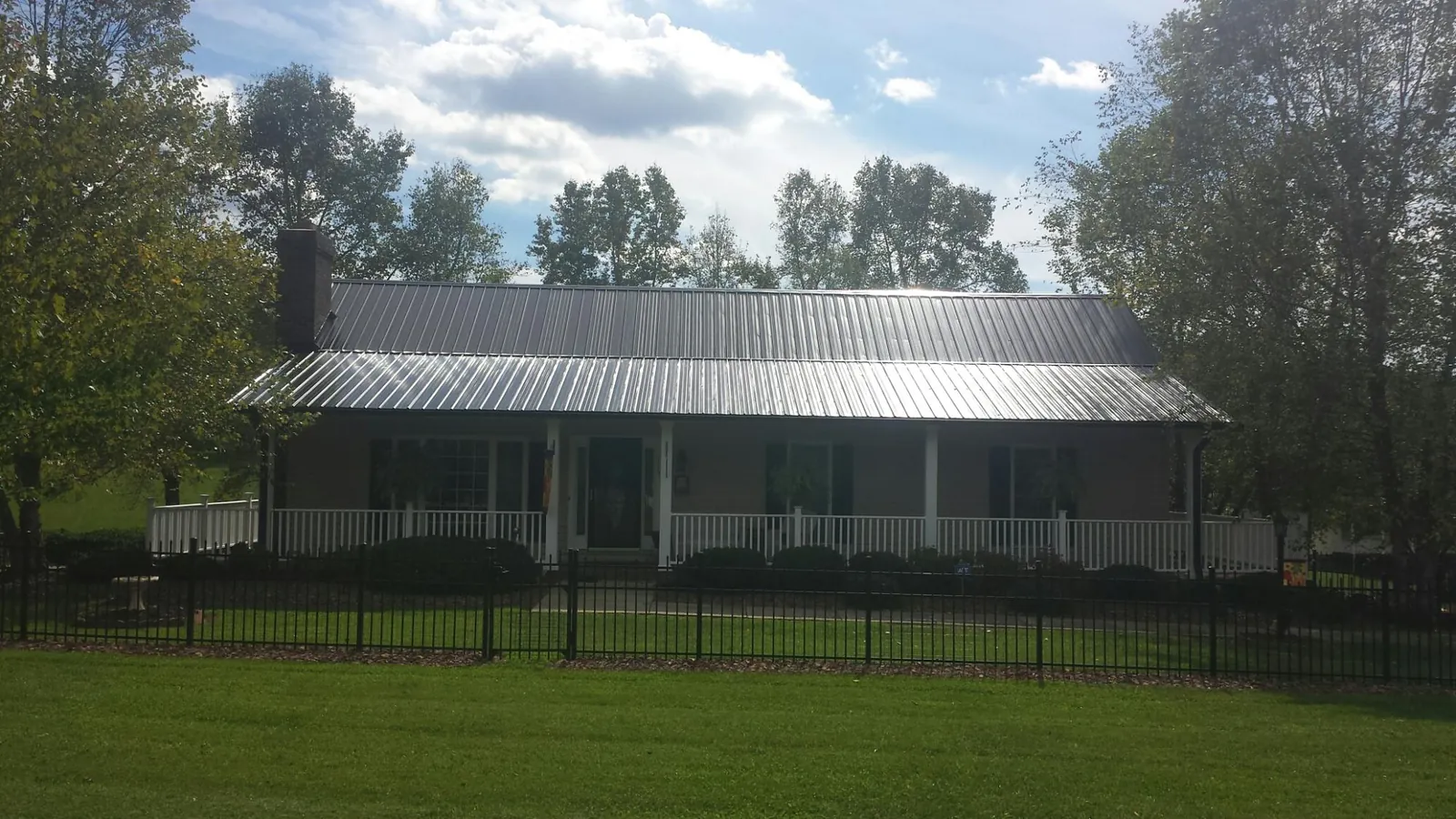 Gray metal roof on a brick ranch with a full width front porch — Gutter Guard Installation work by our crew in Alexander