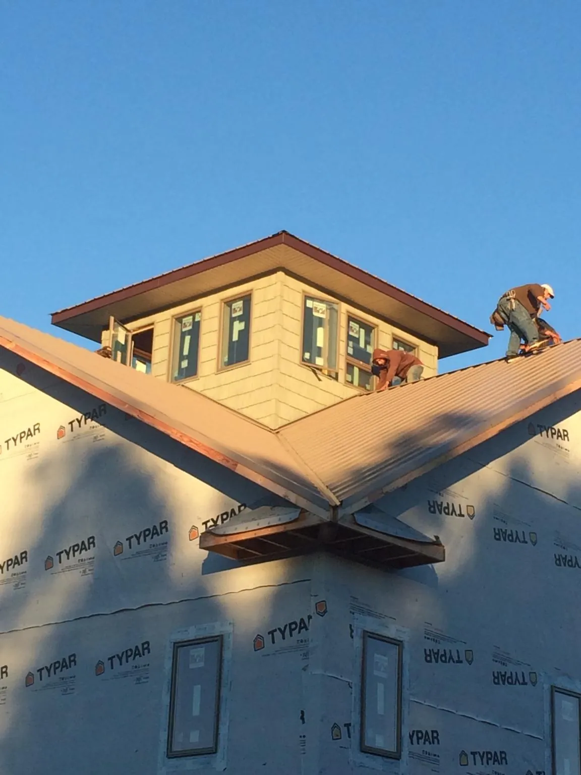Roofers working around a rooftop cupola on a new metal roof at sunset — Roof Waterproofing in Alexander by Roofing Brothers